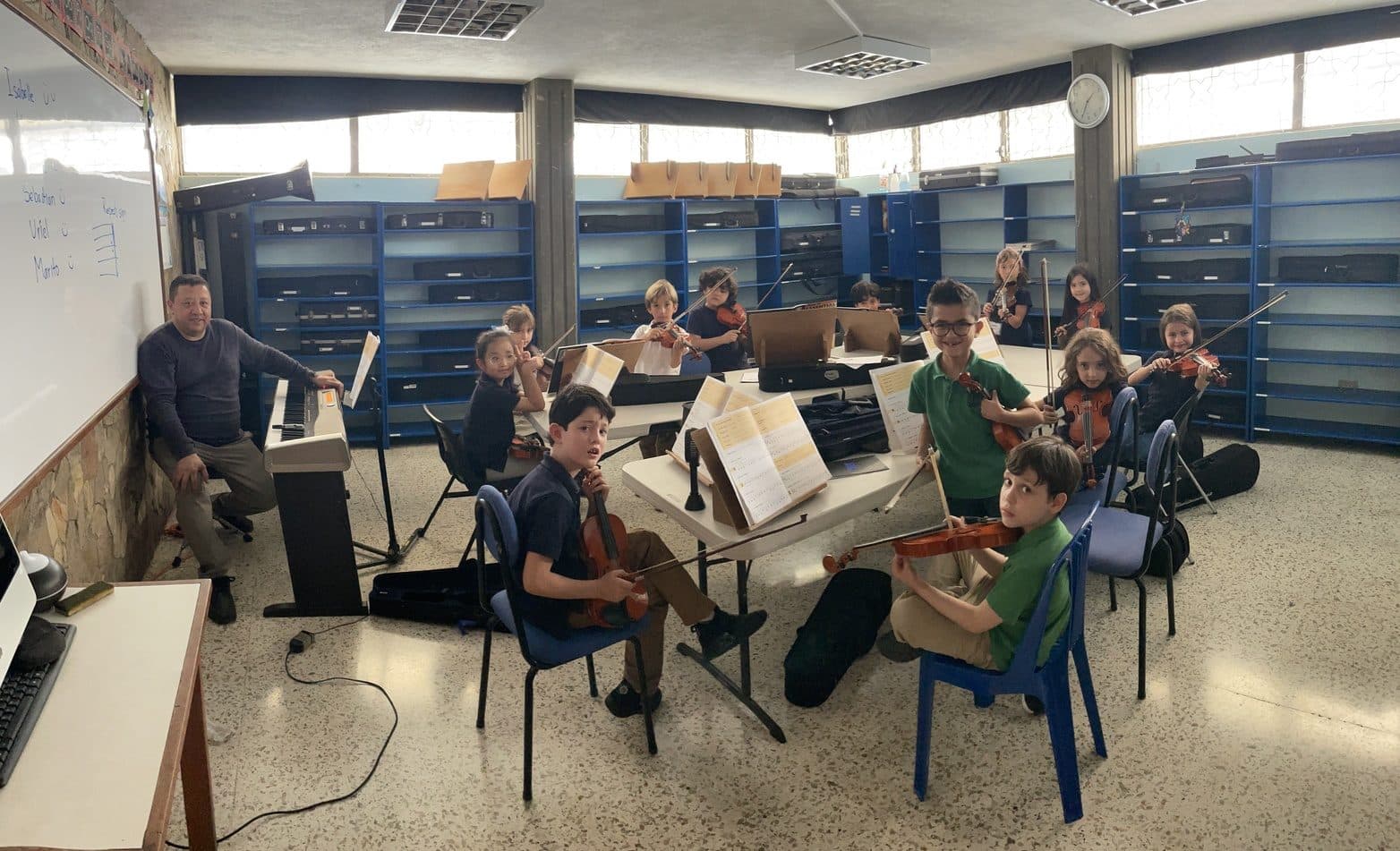 A small group of young students in a classroom string rehearsal