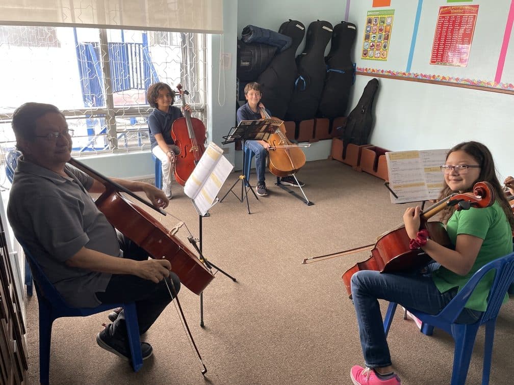 A teacher and students in a small-group cello lesson