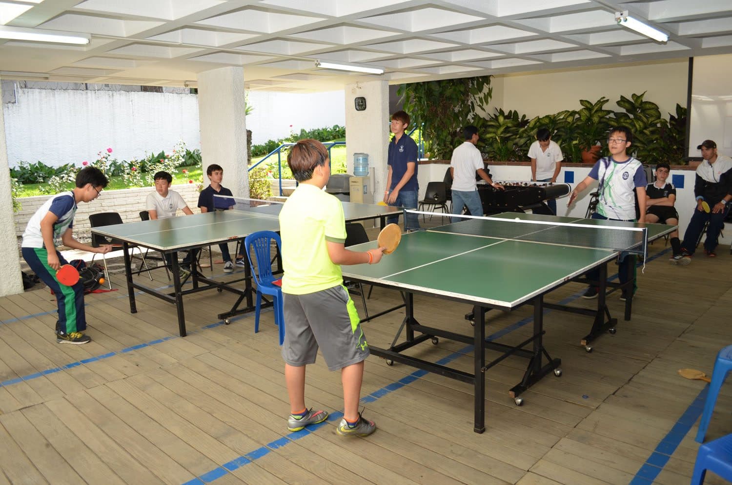 Students playing table tennis in the covered court